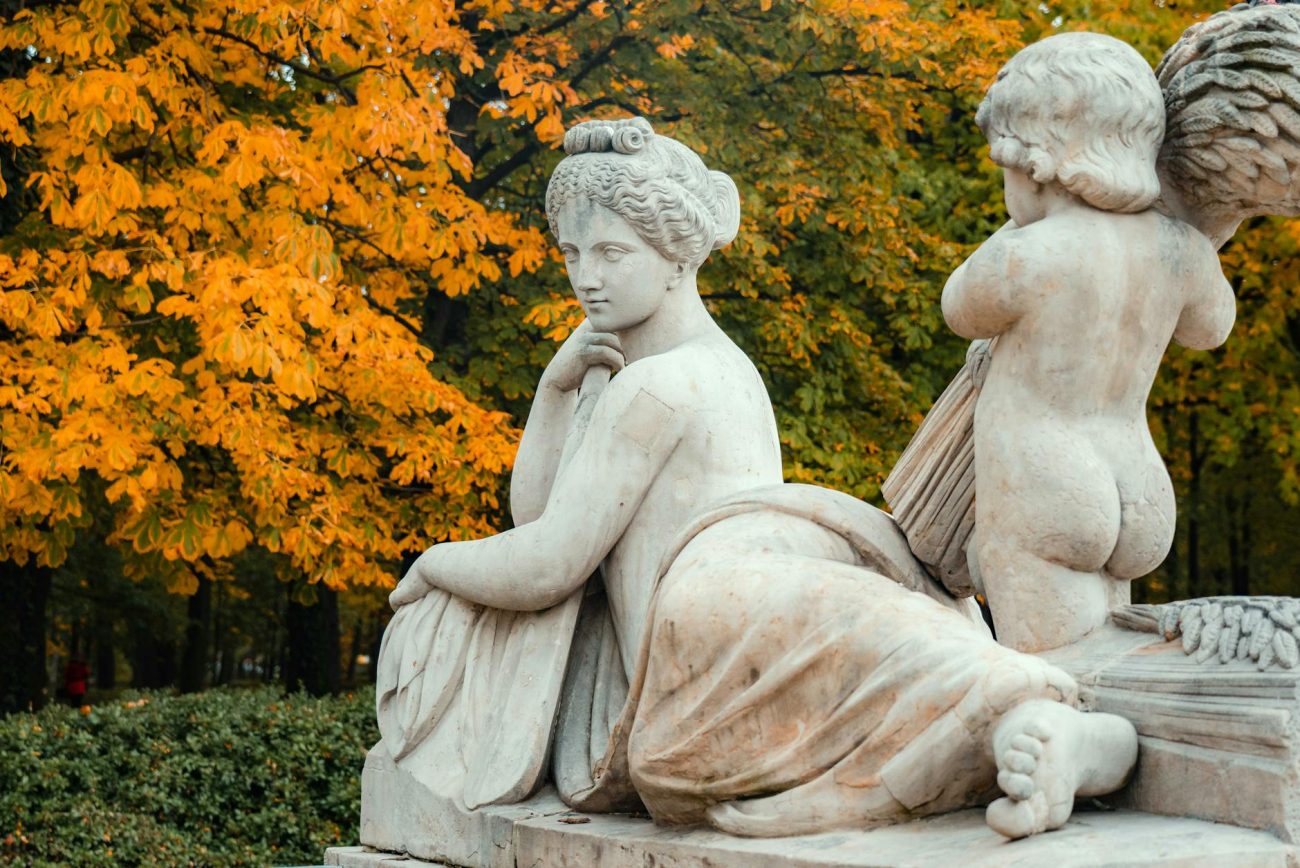 Marble sculpture with autumn foliage background in a serene park setting.