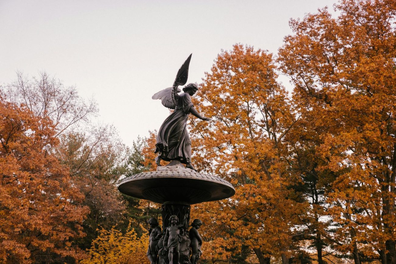 Iconic Bethesda Terrace Angel statue in autumn with vibrant foliage in New York's Central Park.