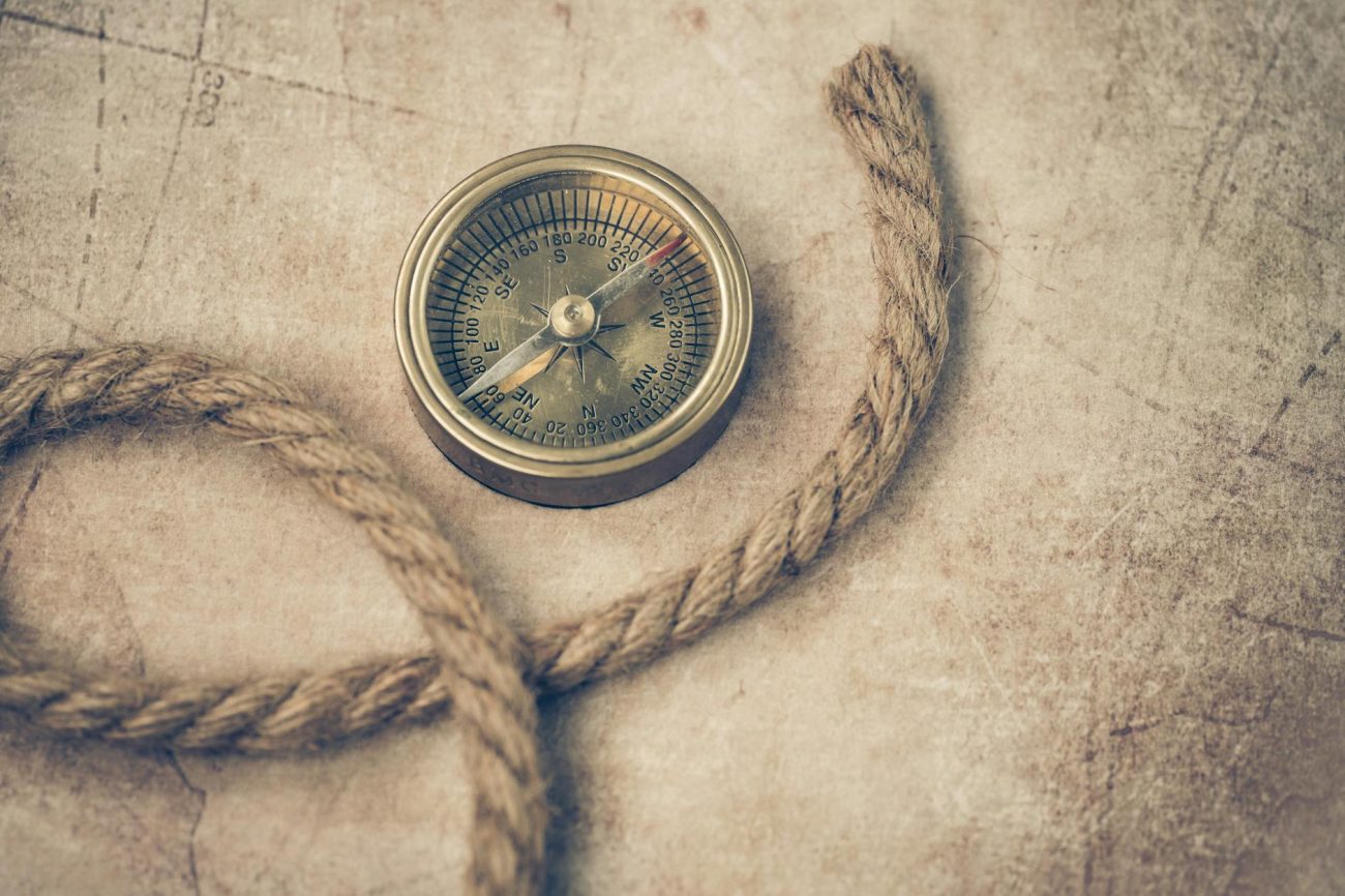 An old compass and rope resting on a vintage map, evoking adventure and navigation.