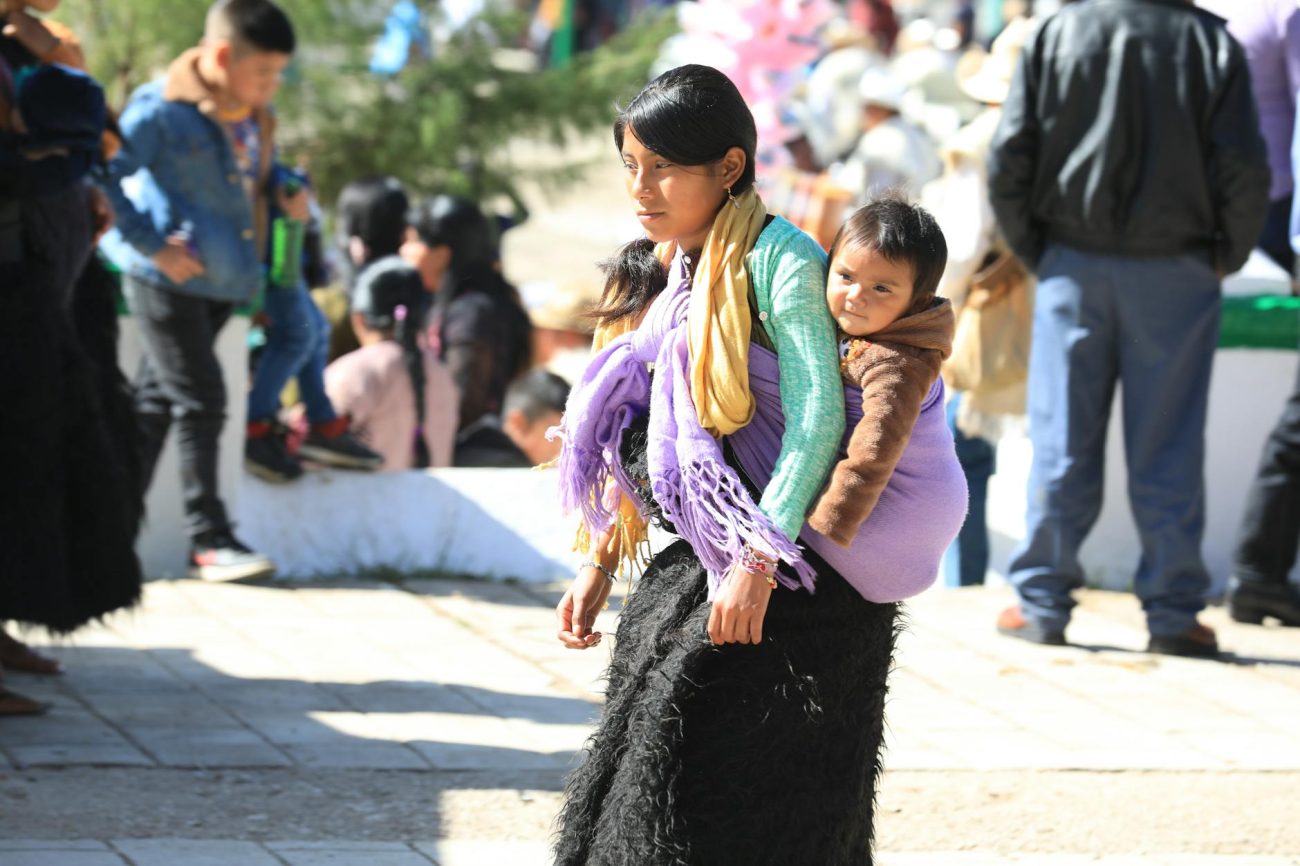 A mother carrying her child using a traditional scarf in Chiapas, Mexico.