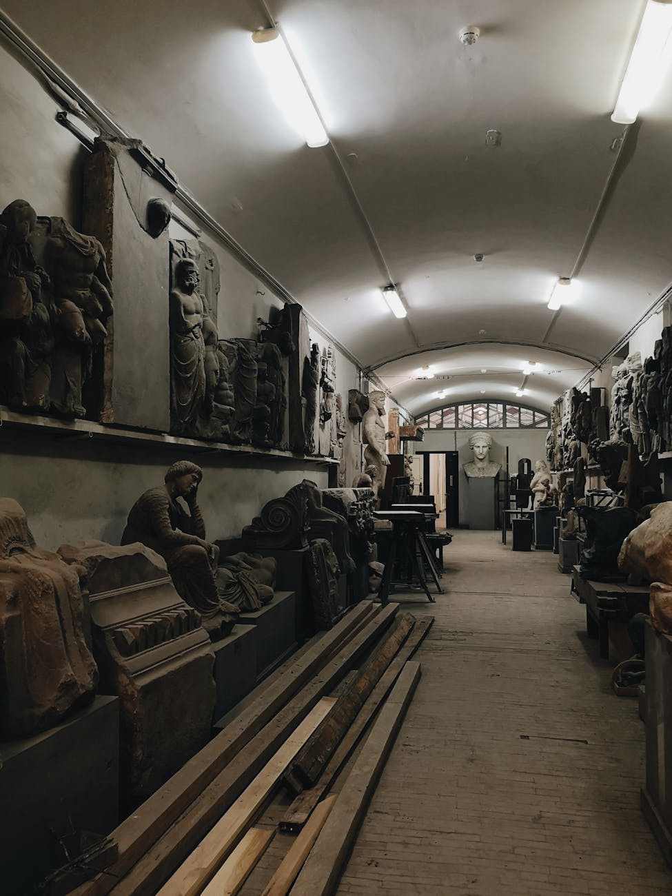 A moody interior view of a corridor lined with ancient sculptures and artifacts.