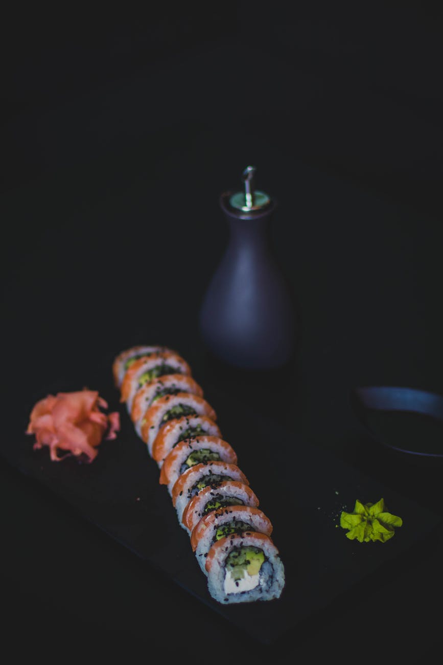 Tasty sushi roll with ginger and wasabi on dark background.