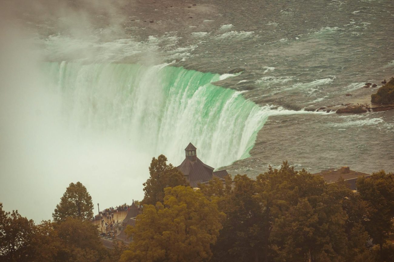 Stunning autumn view of the iconic Horseshoe Falls in Niagara, surrounded by lush trees.