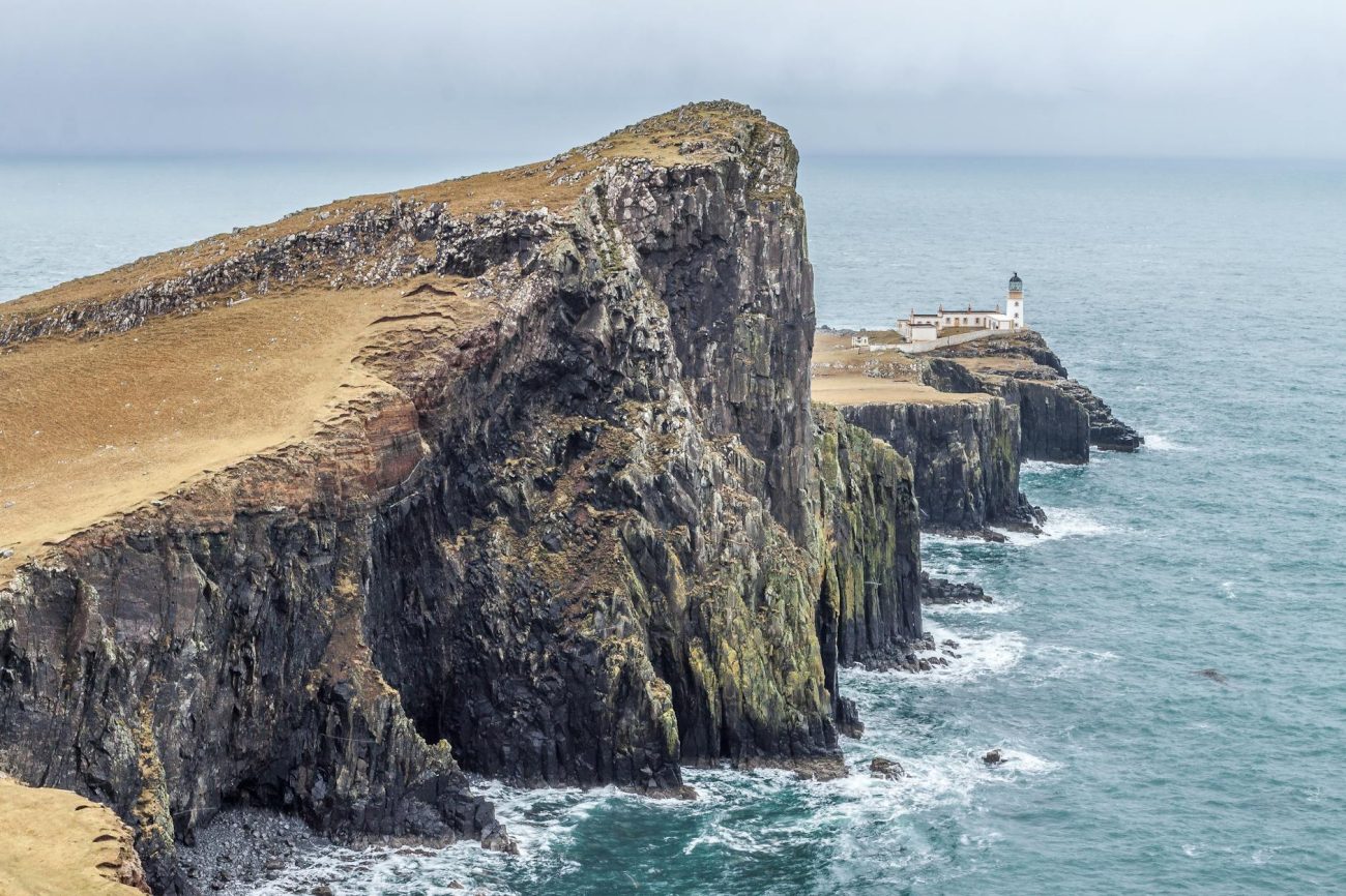 Dramatic cliffs and the iconic Neist Point Lighthouse on the captivating Isle of Skye coastline in Scotland.