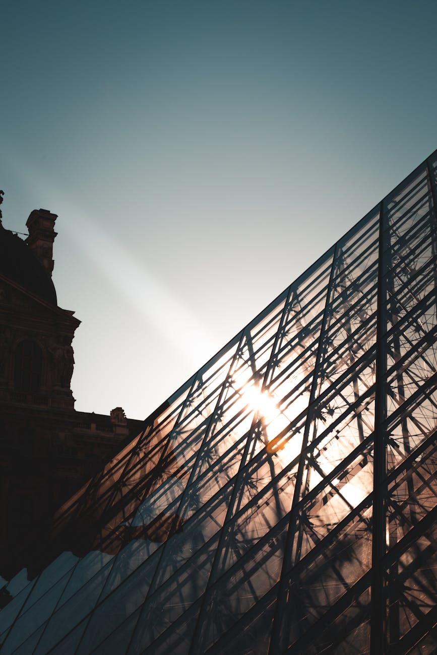 Beautiful sunset view of the Louvre Pyramid, capturing light reflections on the glass structure in Paris.