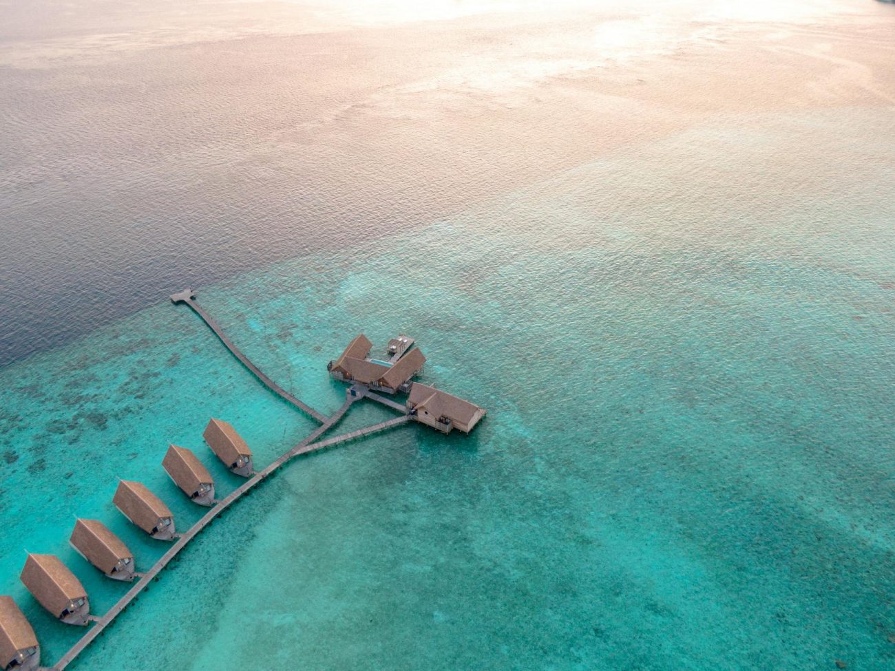Stunning aerial view of overwater bungalows in Guraidhoo, Maldives showcasing turquoise water and resort architecture.