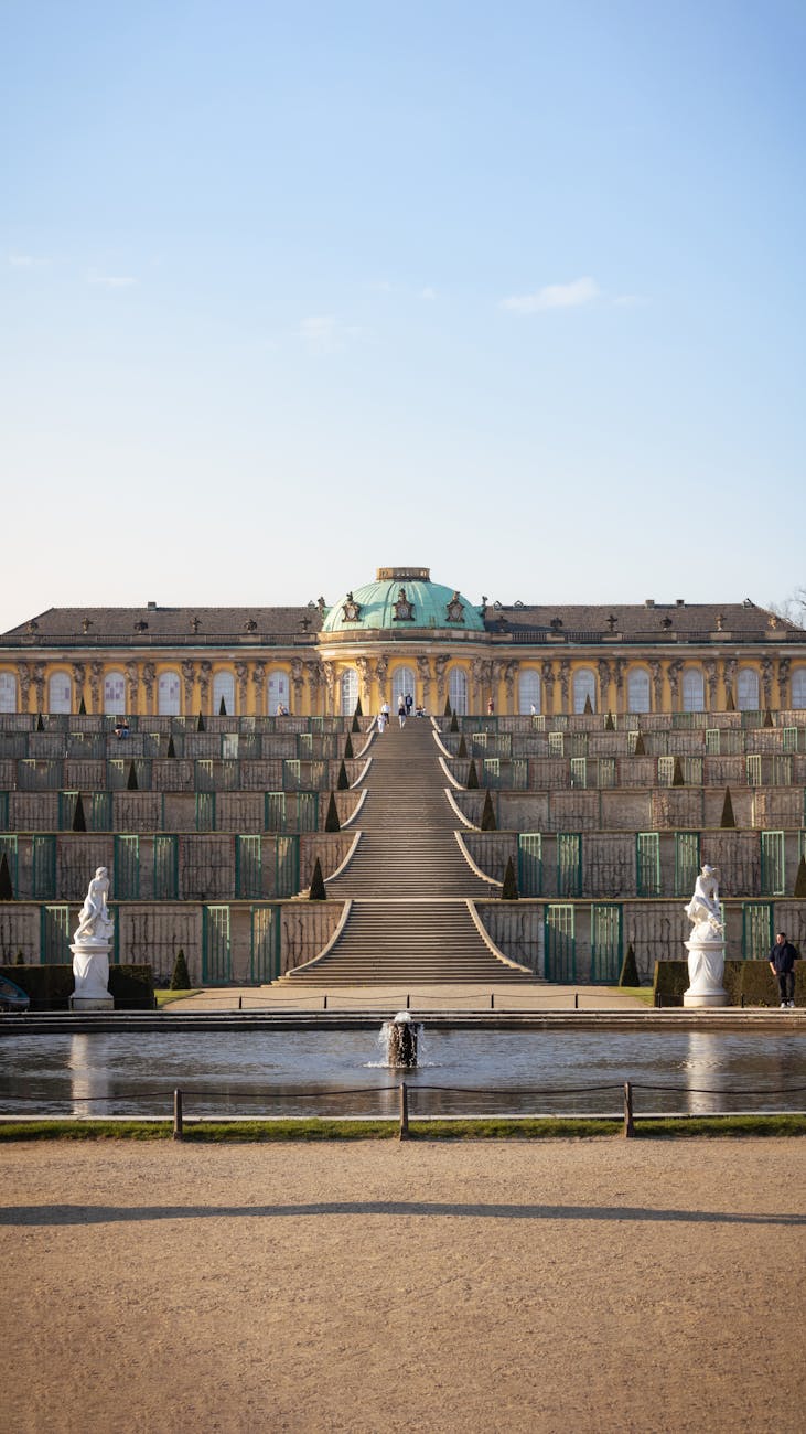 A breathtaking view of Sanssouci Palace's grand staircase and fountain under a clear blue sky.