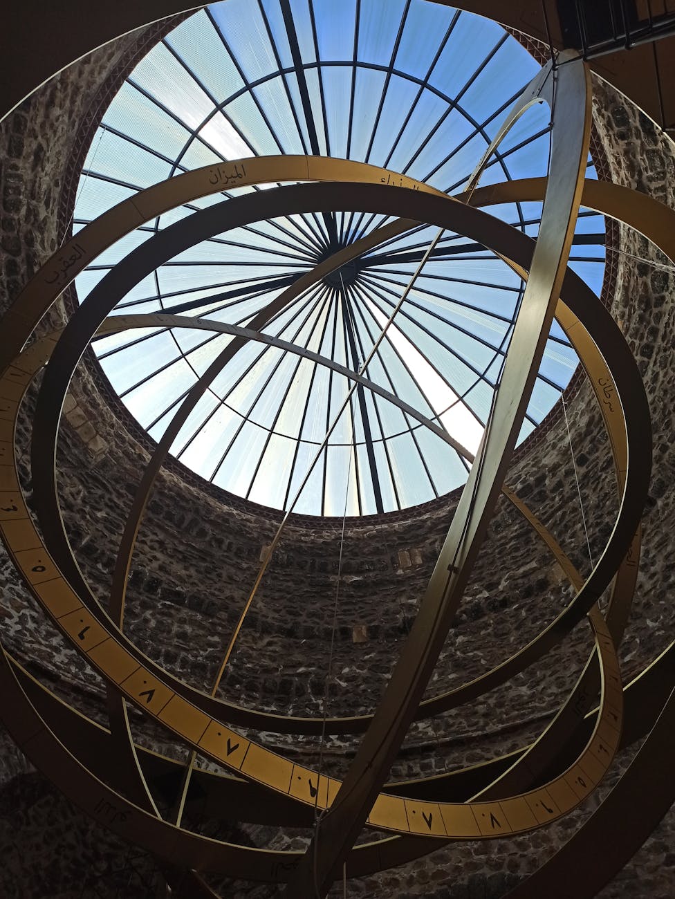 Intricate spherical sculpture with skylight dome in a museum setting.