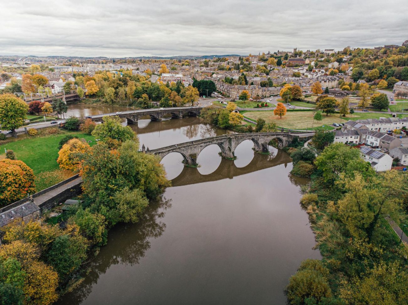 An aerial shot of Stirling Bridge with autumn foliage in Scotland, showcasing historical architecture.