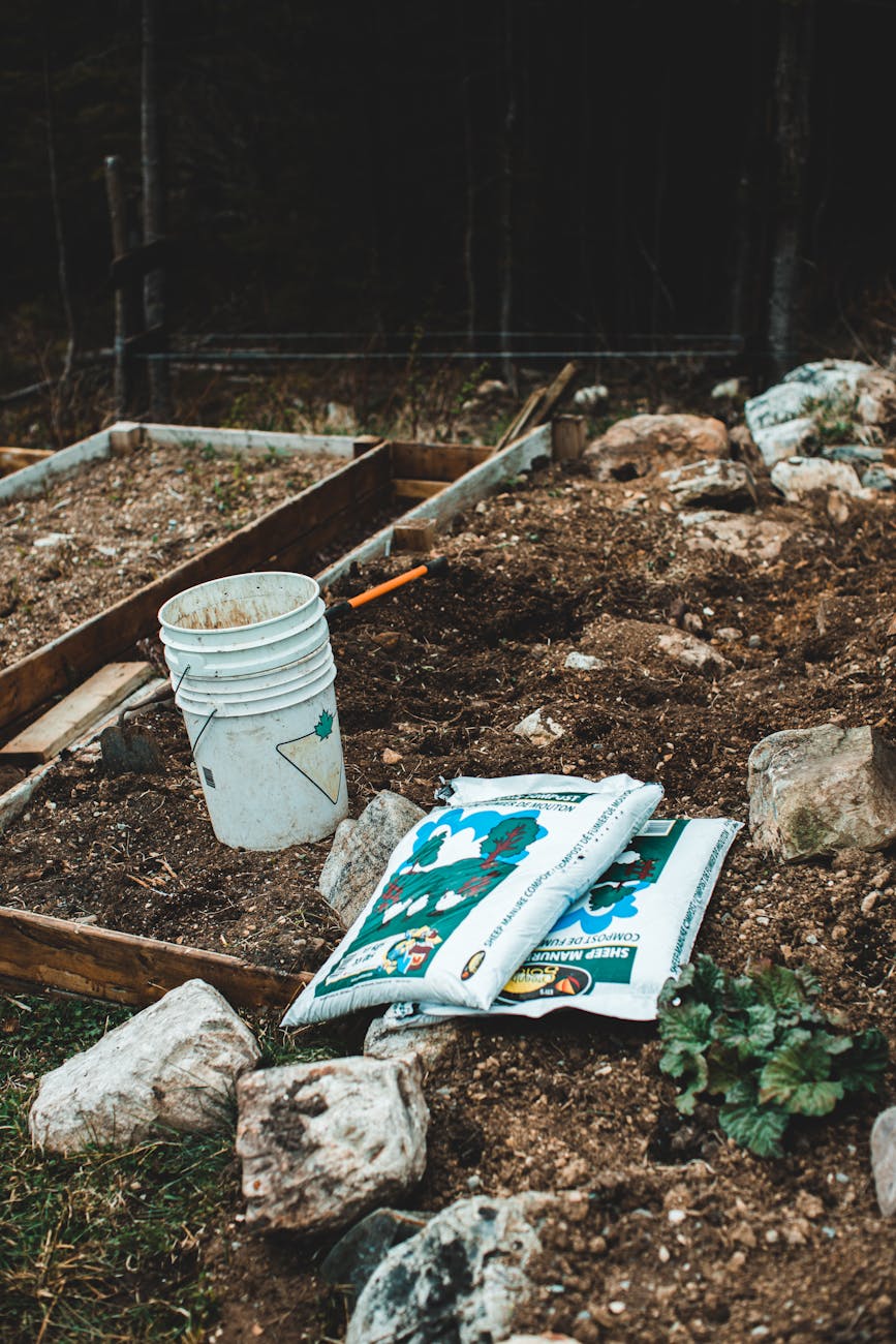 White bucket and gardening supplies on soil, perfect for outdoor gardening themes.