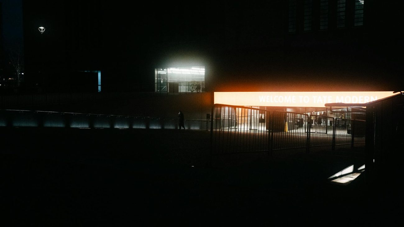 A night view of Tate Modern's entrance sign in London, featuring urban lighting.
