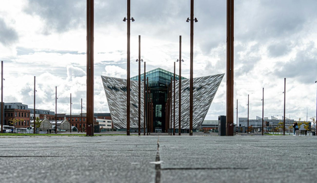 The striking modern architecture of Titanic Belfast under a cloudy sky.