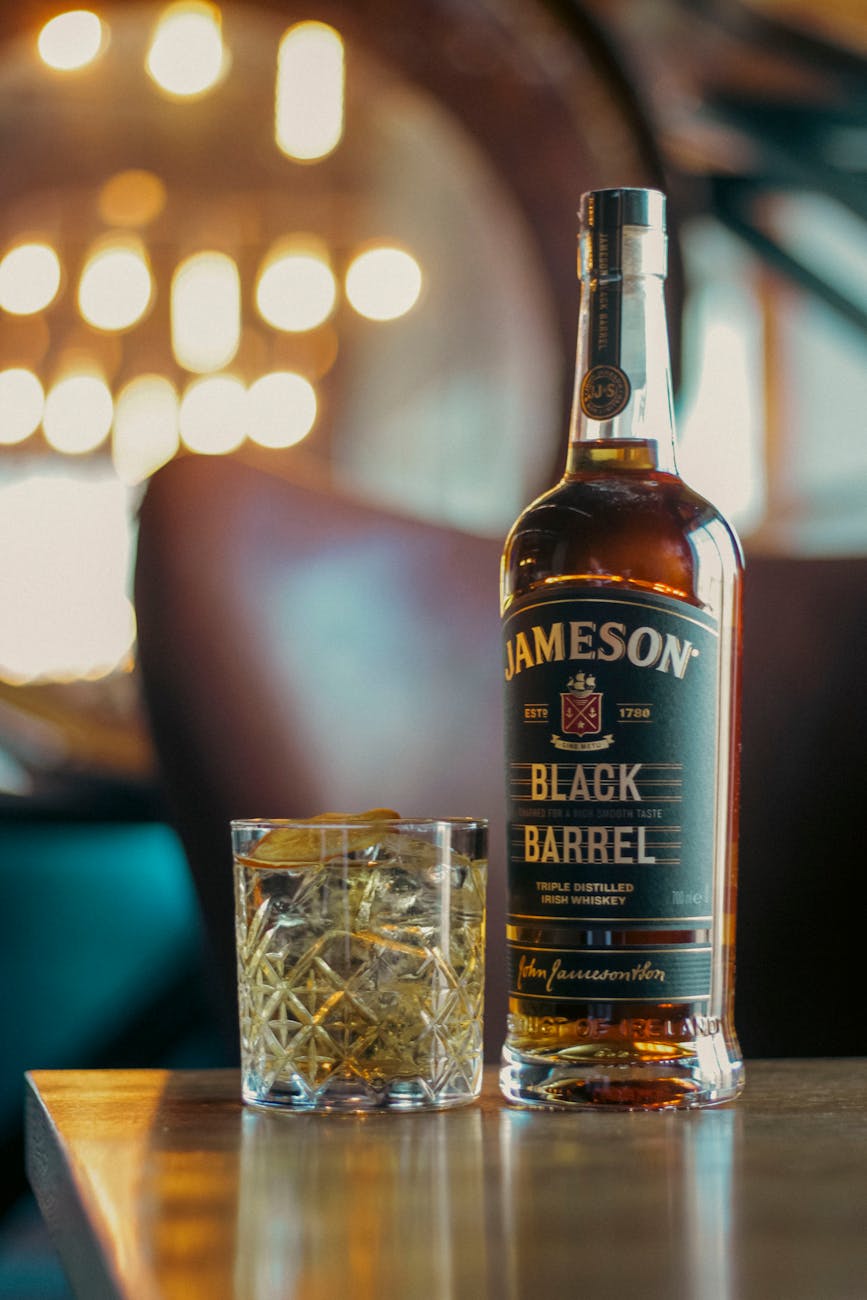 Close-up of a whiskey bottle and glass on a wooden table, capturing a warm ambiance.